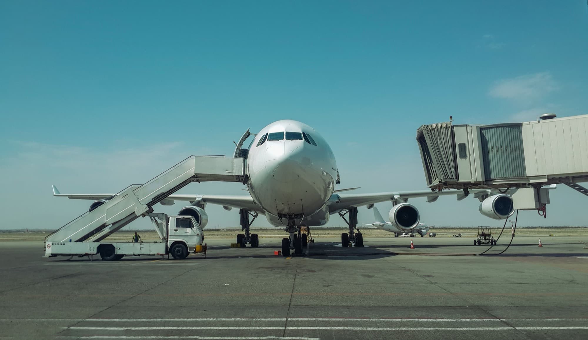An aircraft parked at an airport gate with the jet bridge attached