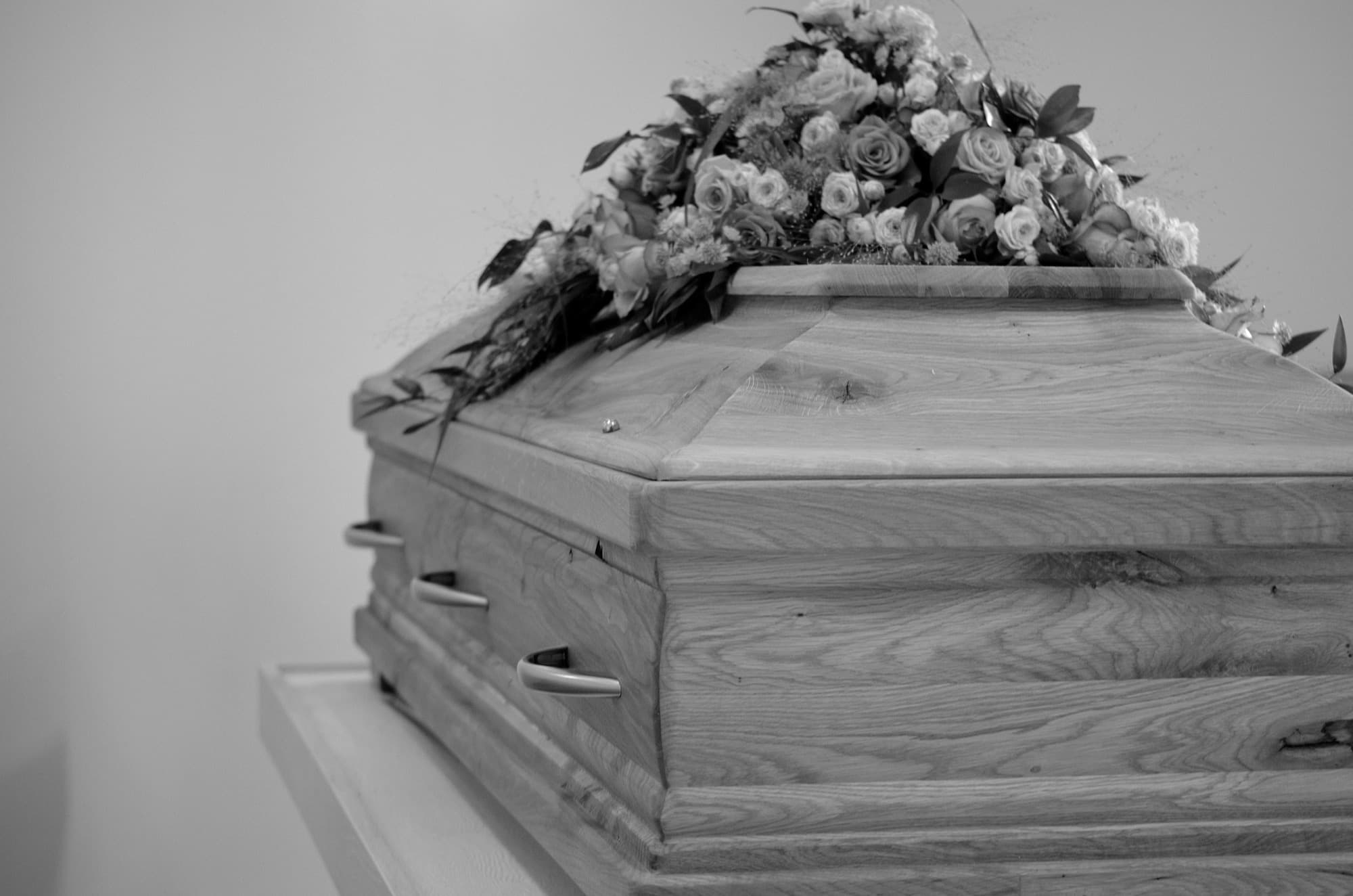 A casket with a floral spray, photographed in black and white