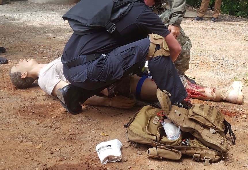 A tactical medical training scenario, treating a simulated casualty with a trauma bag deployed